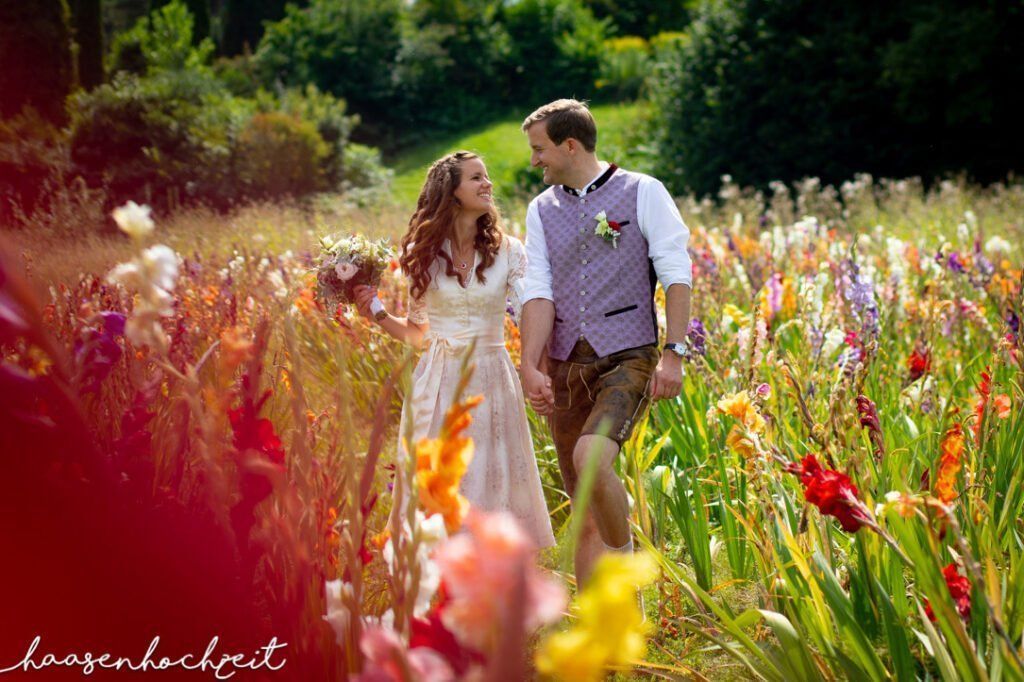 Brautpaar läuft durch bunte Blumenwiese